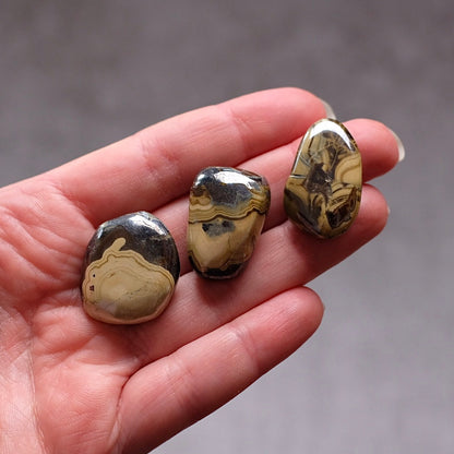 Three marbled stones held in a hand against a neutral background